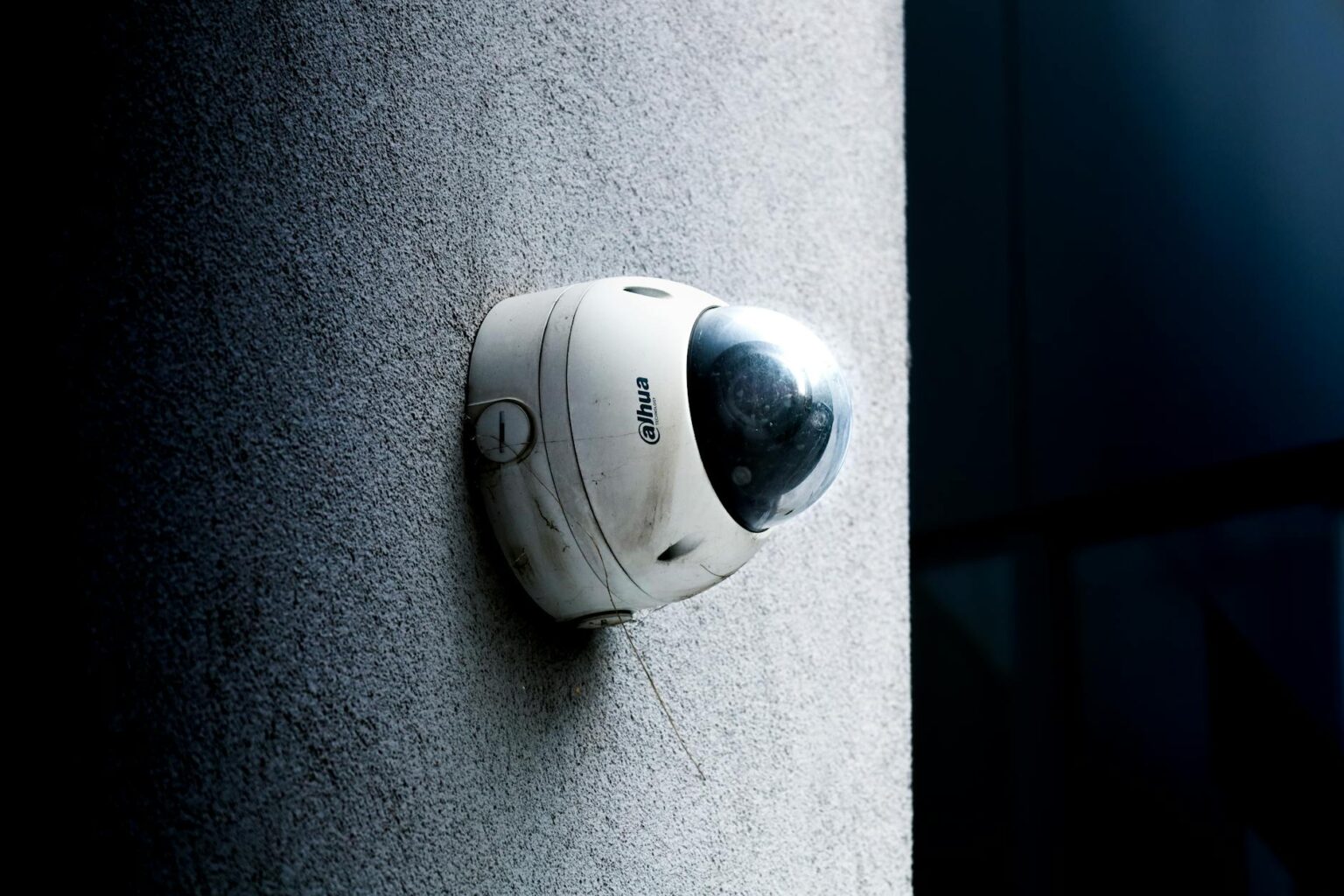 Modern white security camera mounted on exterior wall of residential building