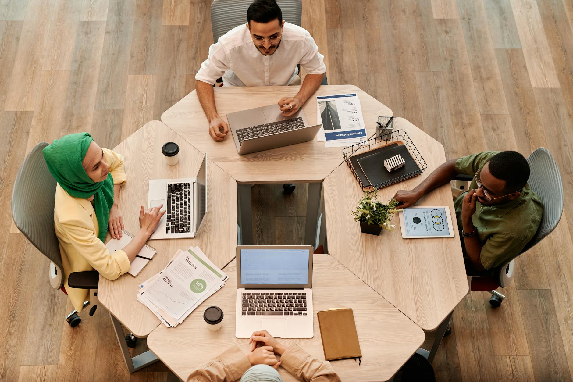 Modern office workspace with team members collaborating around computers and documents