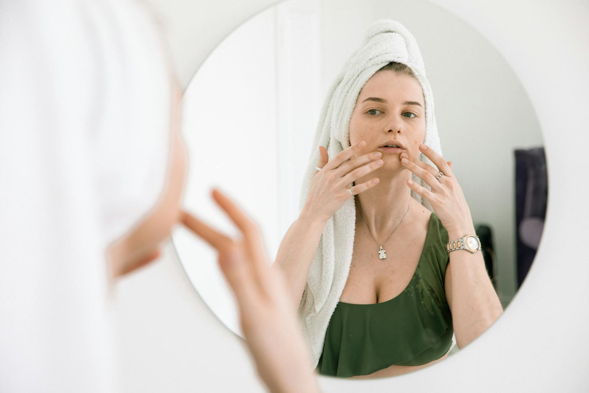 Person using mirror for skincare analysis and beauty routine in bathroom