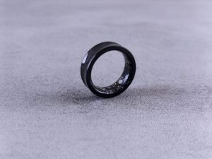 Close-up of a smart ring worn on a finger showing health tracking device design