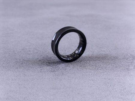 Close-up of a smart ring worn on a finger showing health tracking device design