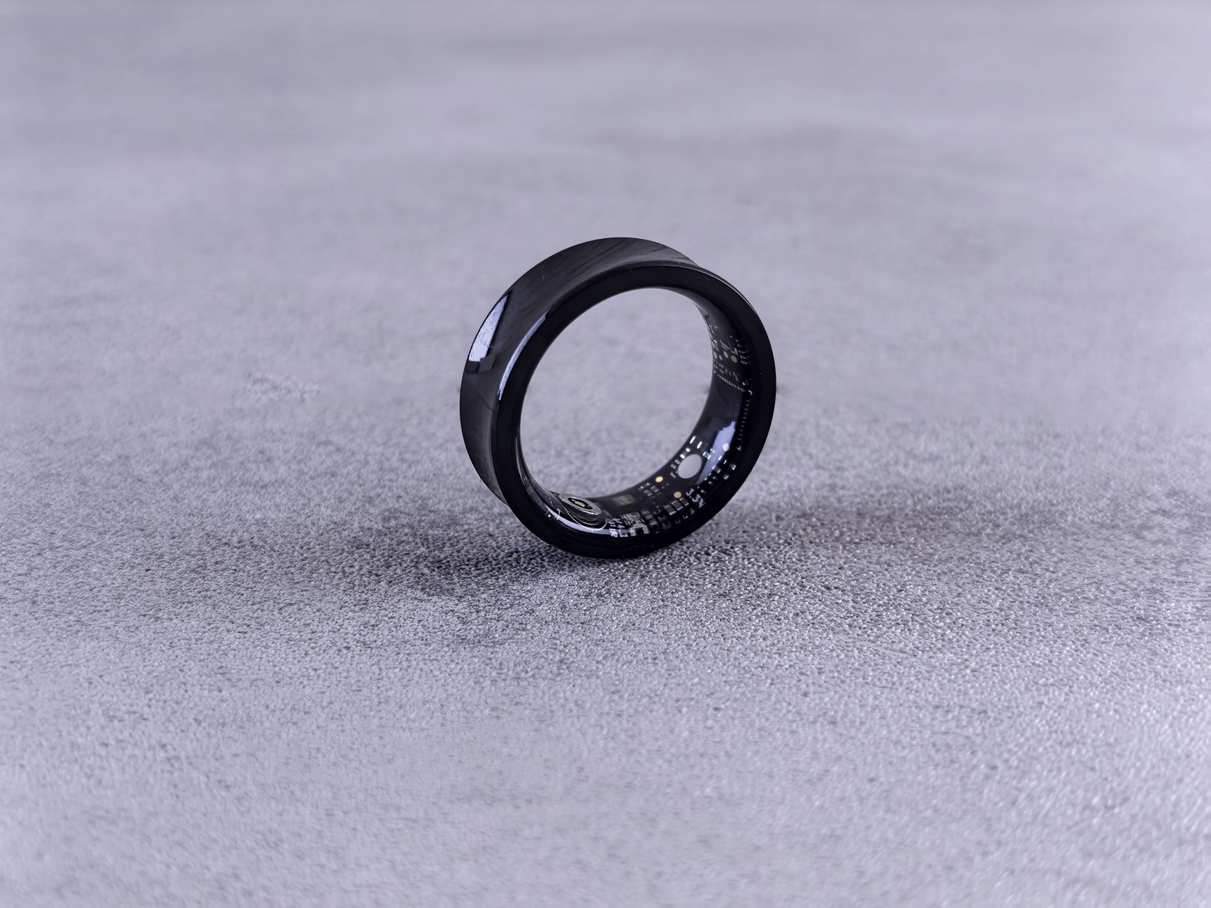 Close-up of a smart ring worn on a finger showing health tracking device design