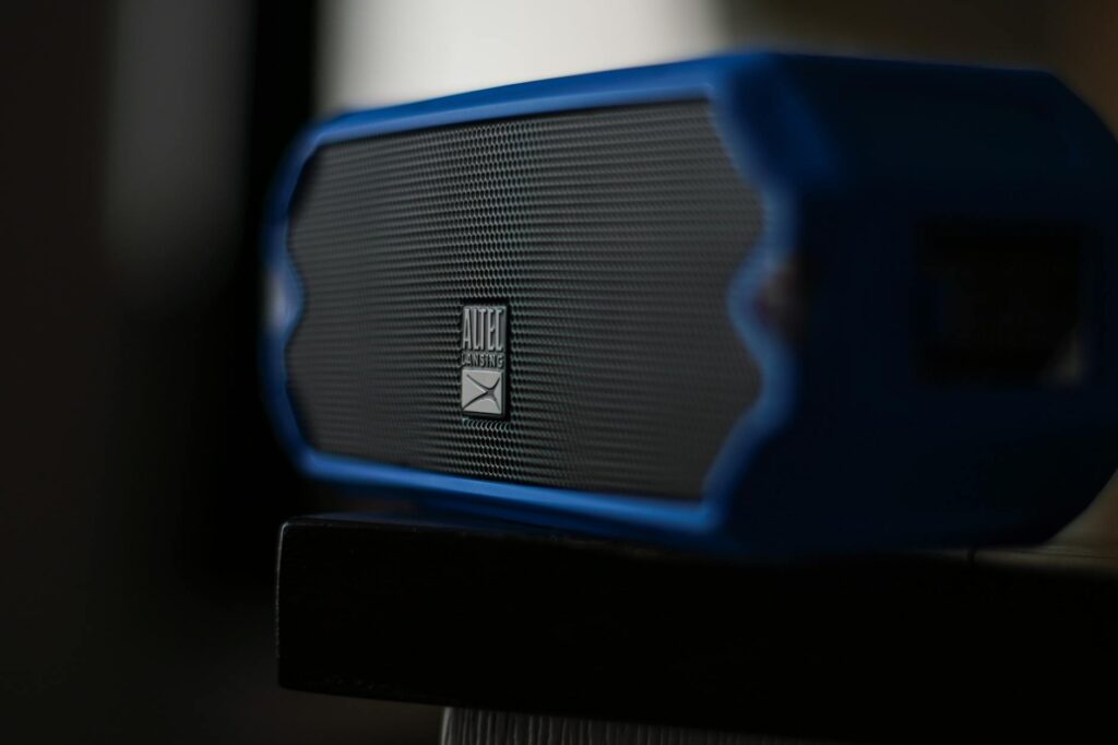 Portable Bluetooth speaker sitting on a wooden table outdoors in natural light