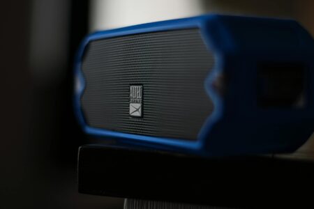 Portable Bluetooth speaker sitting on a wooden table outdoors in natural light