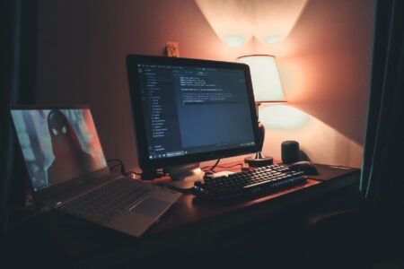 A gaming laptop open on a desk with RGB keyboard lighting visible