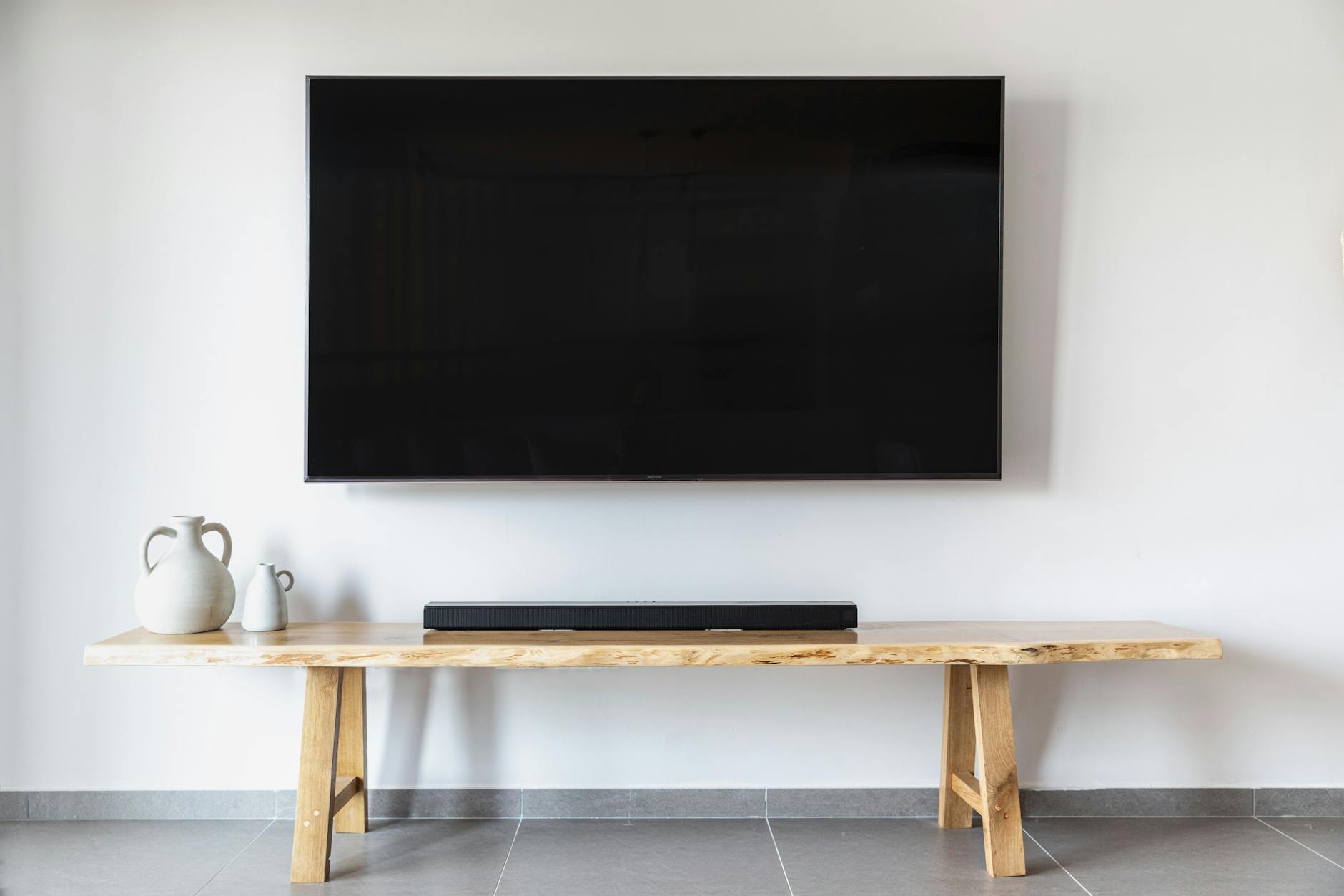 Close-up of a sleek premium soundbar speaker on a wooden TV stand
