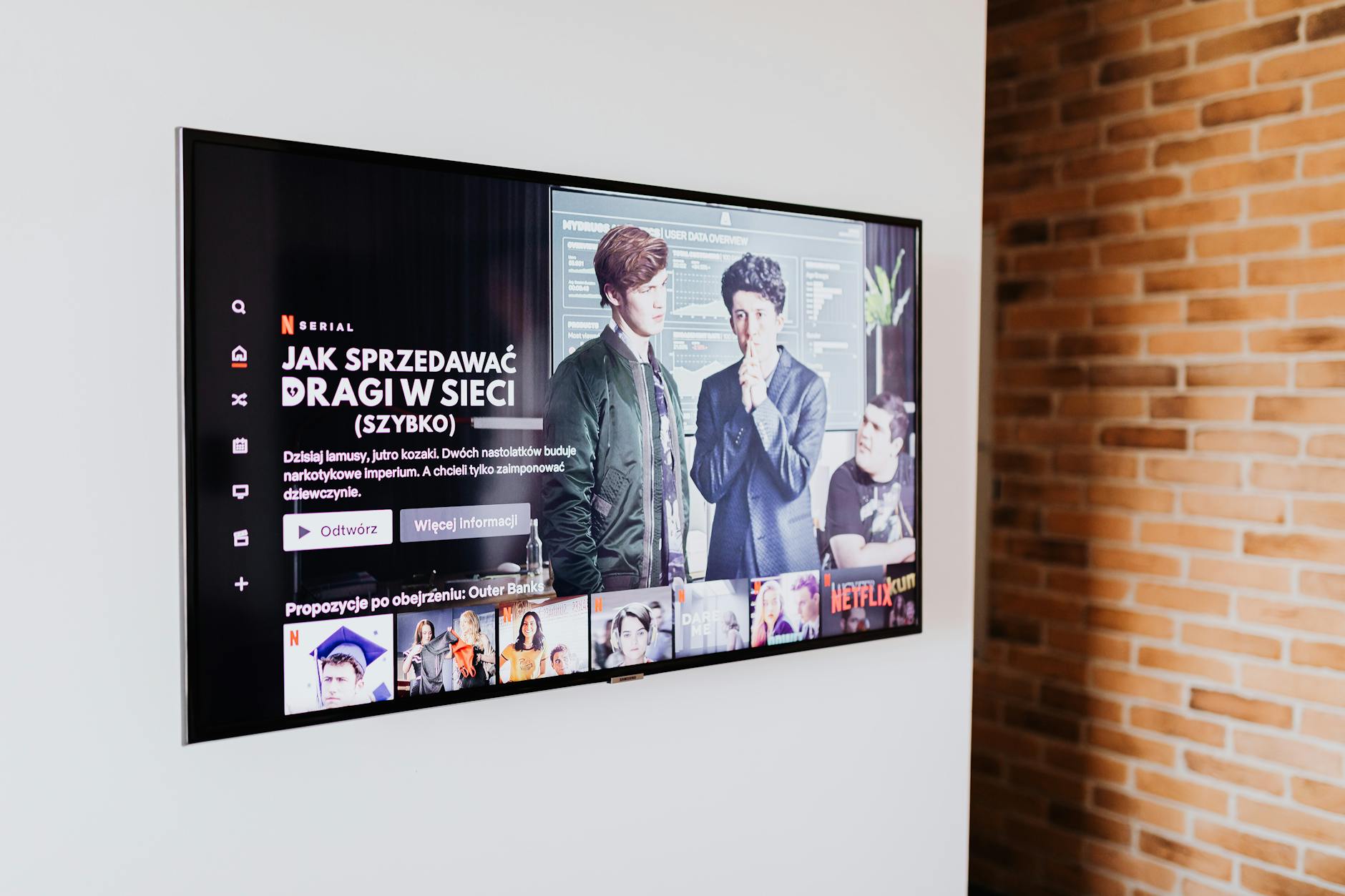 A bright living room with a wall-mounted TV and minimalist audio setup