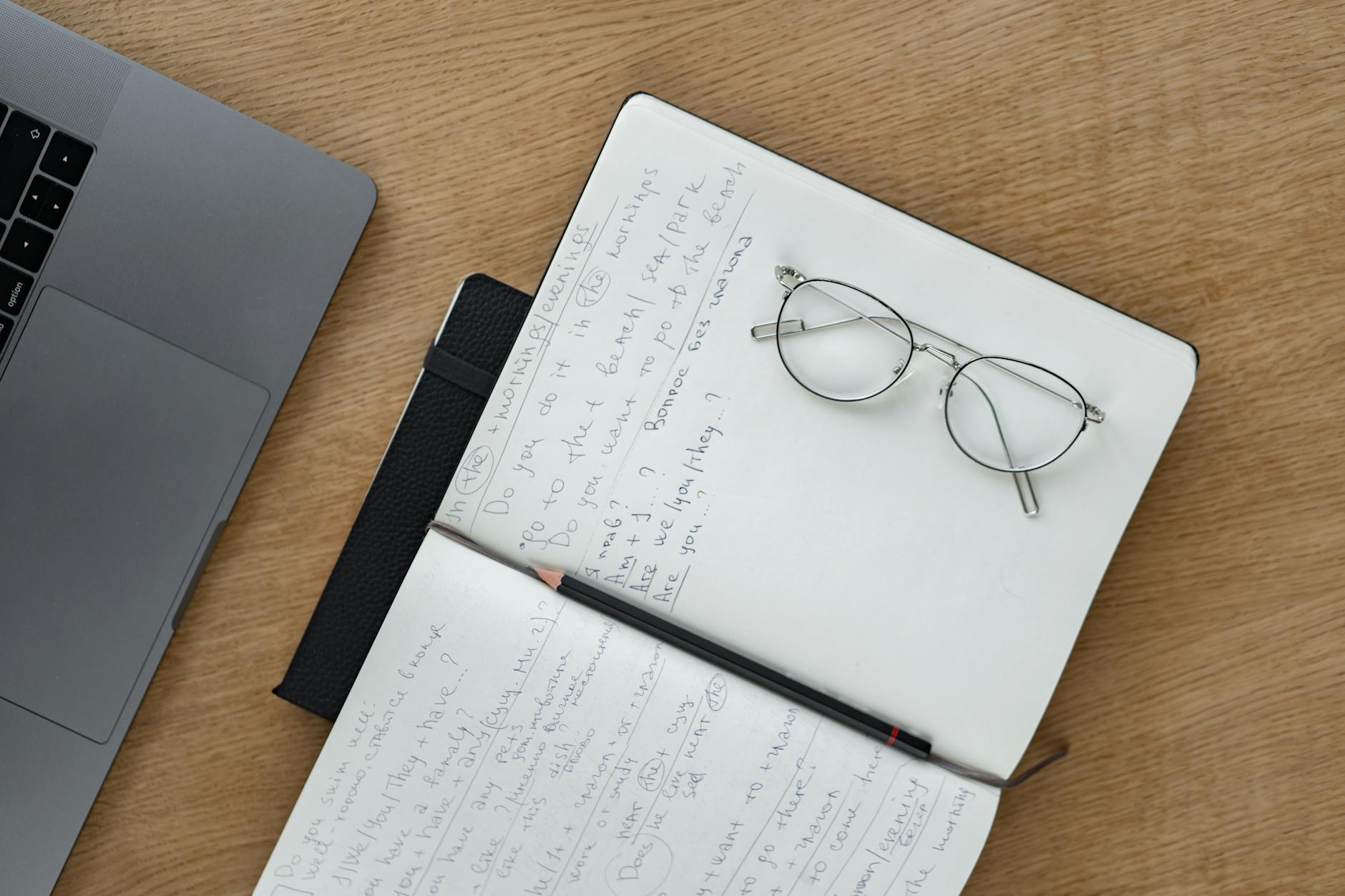 A laptop open on a desk with note-taking app visible on screen