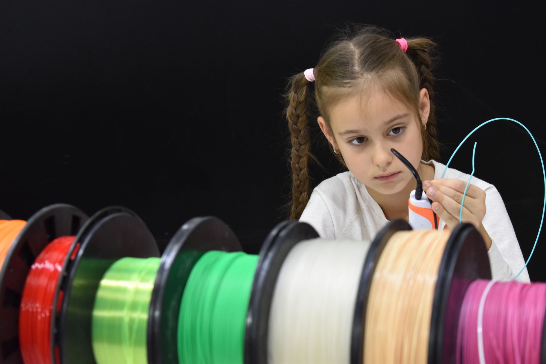 Colorful spools of 3D printing filament lined up on a workshop shelf