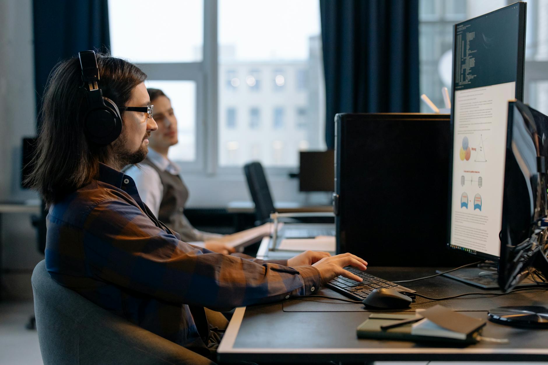 Two developers collaborating on code together at a shared workstation