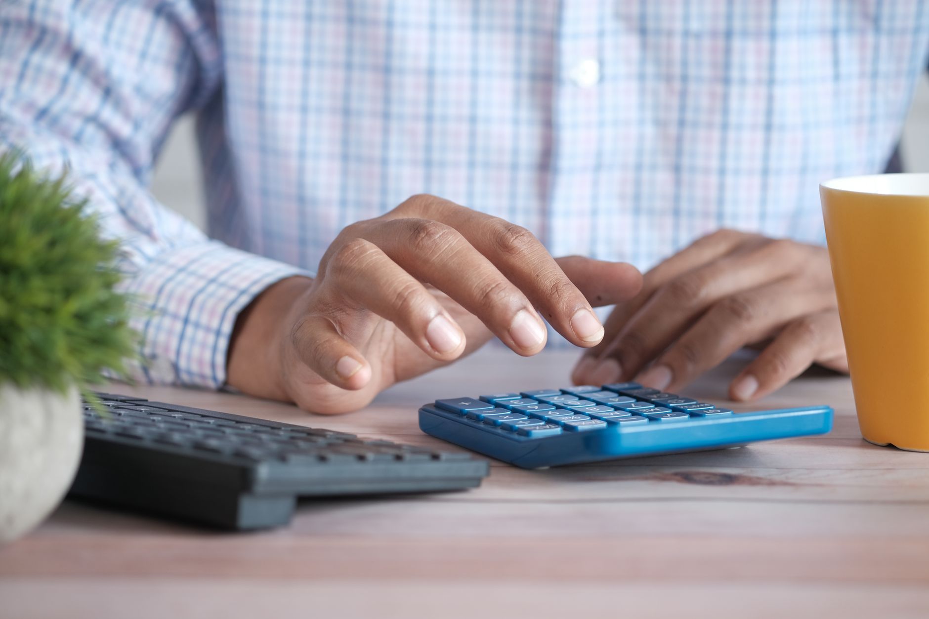 A person reviewing a budget spreadsheet on a desk with a laptop and notebook
