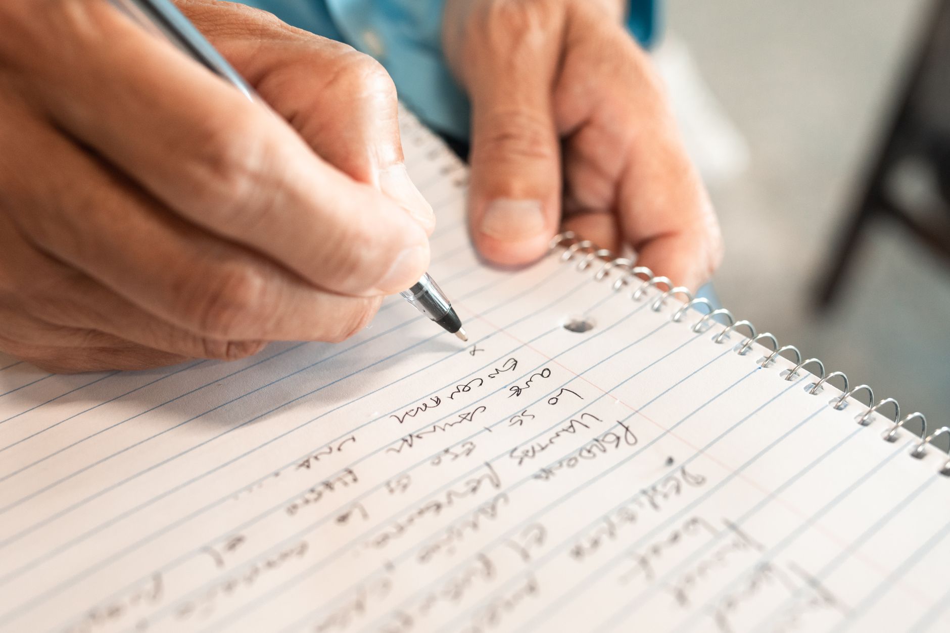 A person typing notes on a laptop in a casual workspace setting