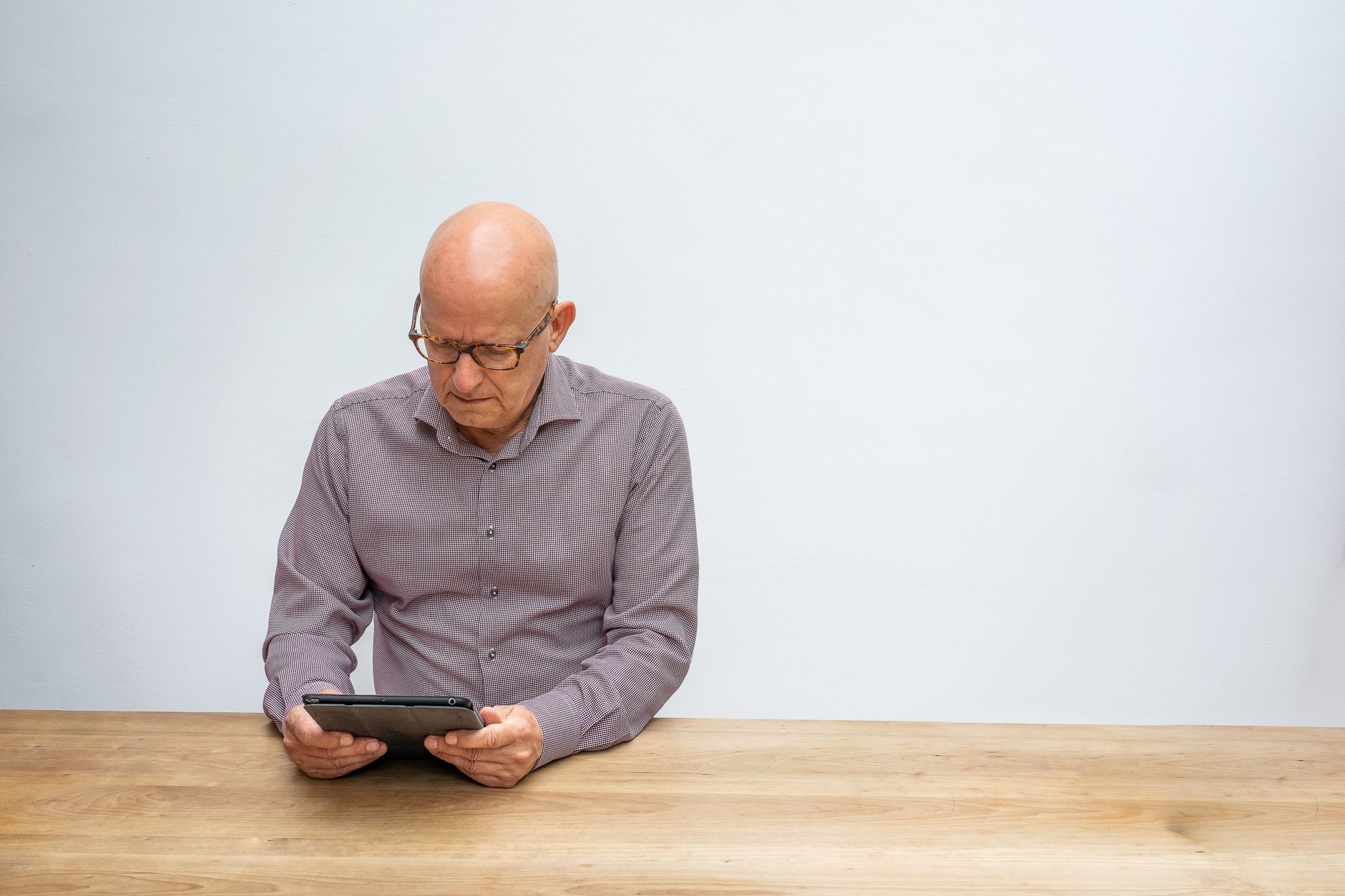 Person reading on a tablet at a desk with a cup of coffee nearby
