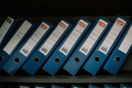 Set Up Paperless-NGX as a Self-Hosted Document Archive A stack of paper documents next to a flatbed scanner on a desk