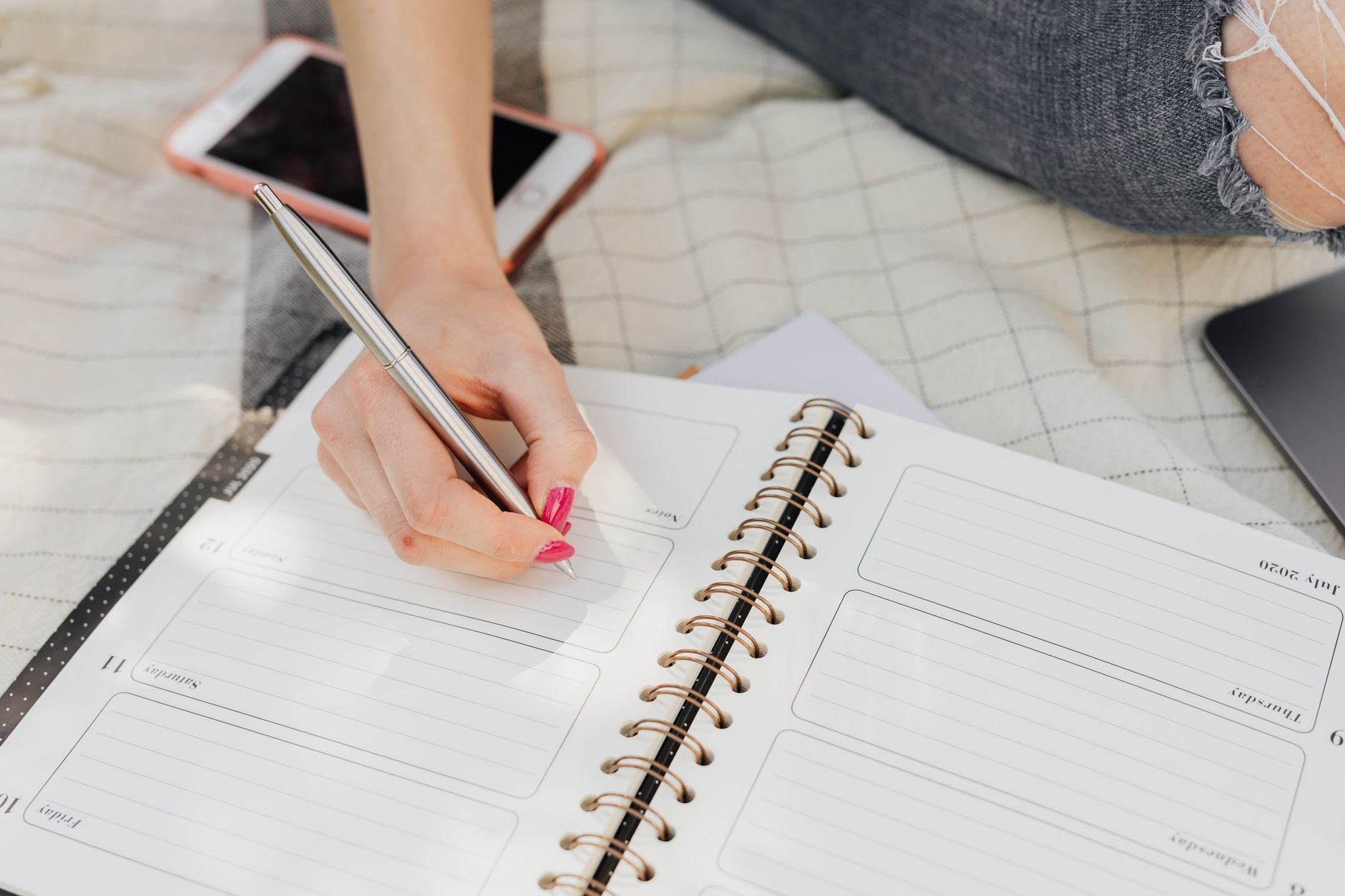 A weekly meal plan written in a notebook with vegetables on the side